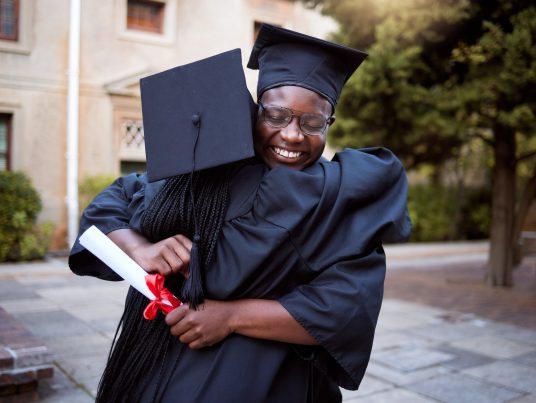 Black people, hug and celebration in graduation ceremony, university degree success or school diplo